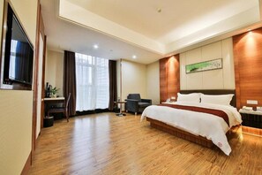 A hotel room with a large bed, a desk with a chair, a TV, and a window with curtains. - Hong Yang Hotel (Shenzhen)