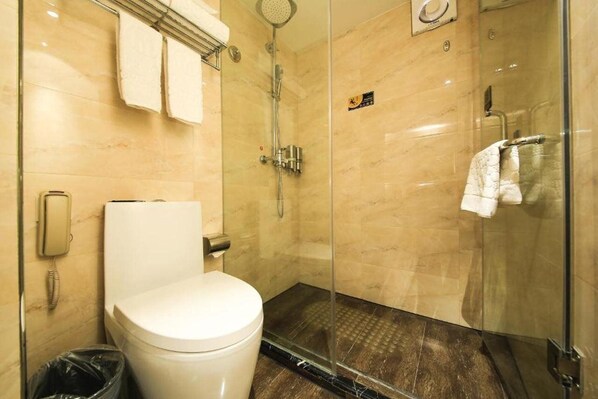 A modern bathroom with a toilet, a glass-enclosed shower, and a hand dryer.