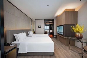 Une chambre d’hôtel moderne avec un grand lit, une télévision et un vase rempli de fleurs jaunes.