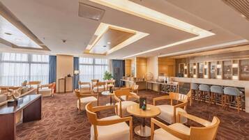 A hotel lobby with a bar area, seating arrangements, and a reception desk.