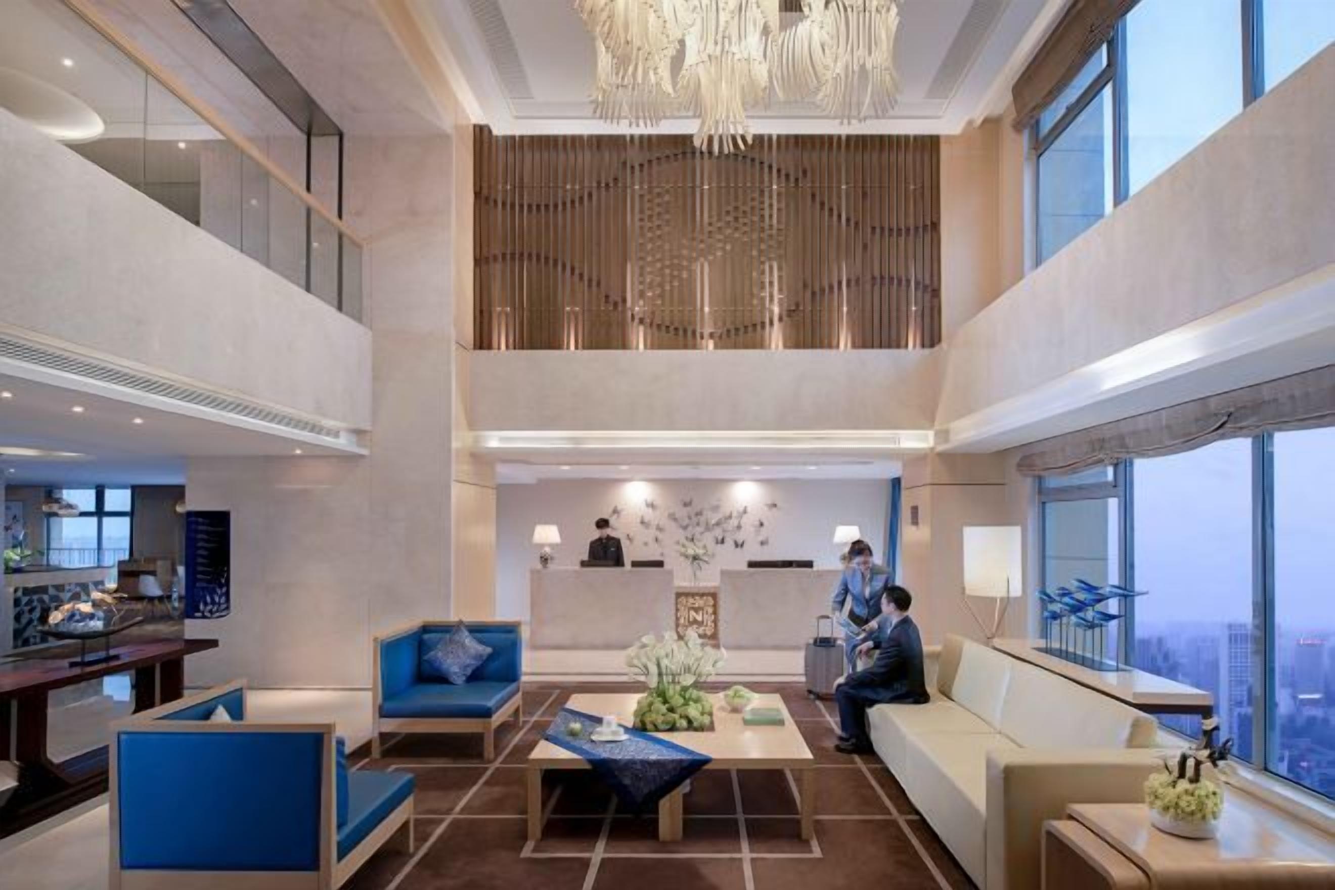 A spacious lobby with a high ceiling, a reception desk, and seating areas.