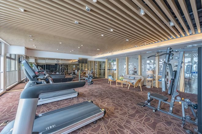 A gym with treadmills, exercise equipment, and a patterned carpet.