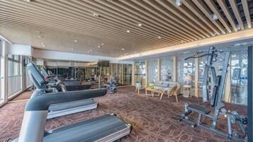 A gym with treadmills, exercise equipment, and a patterned carpet.