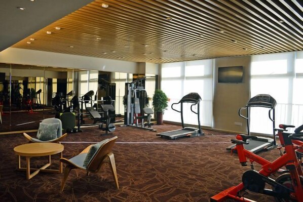 A gym with exercise equipment, seating areas, and large windows. - Novlion Hotel (Shijiazhuang)
