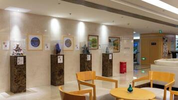 A lobby with marble walls, framed artwork, and a reception desk.