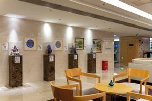 Eine Lobby mit Marmorwänden, gerahmten Kunstwerken und einem Empfangsbereich.