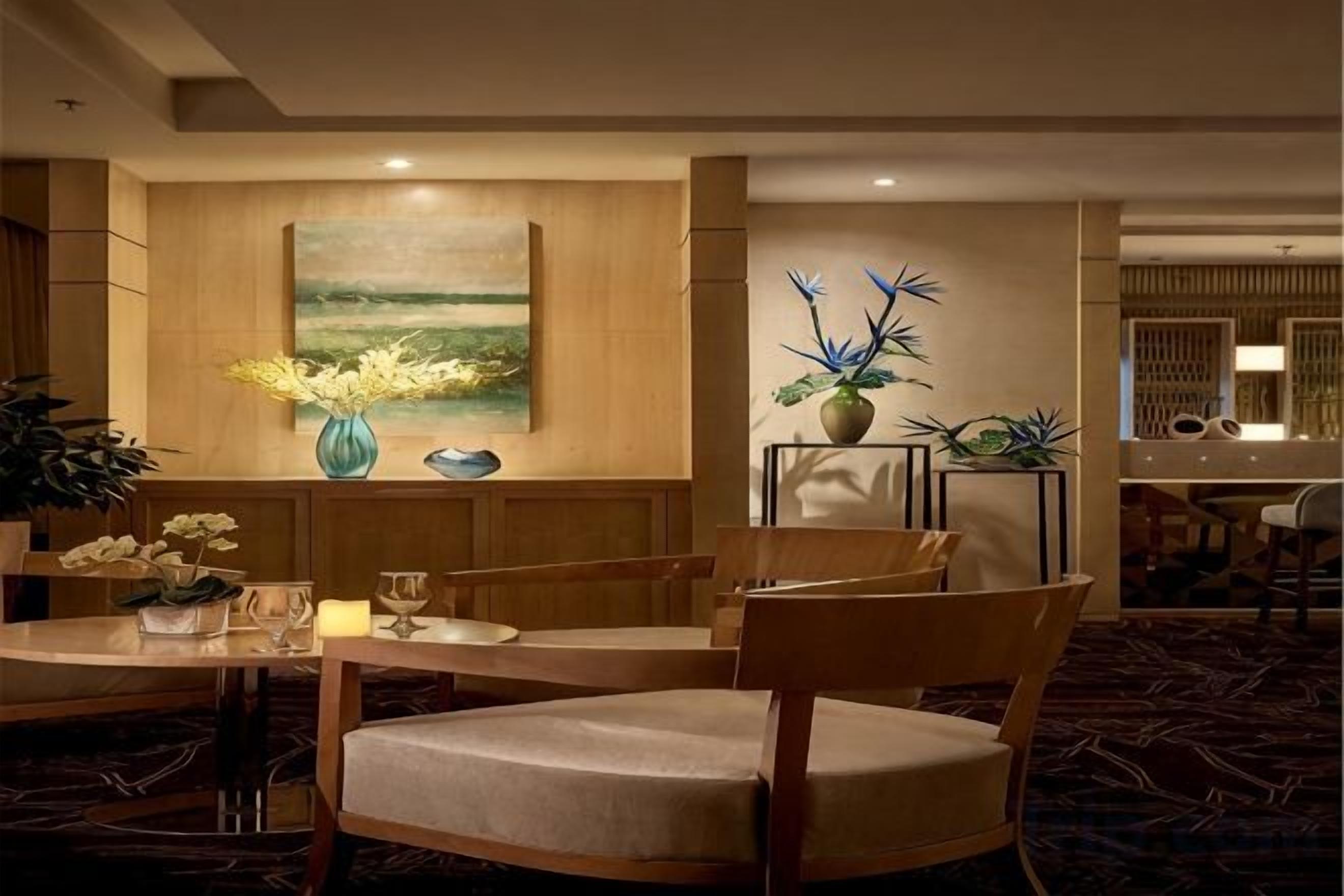 A hotel lobby with a dining area, a painting on the wall, and a reception desk.