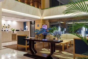 A modern hotel lobby with a reception desk, seating area, and decorative elements. - Novlion Hotel (Shijiazhuang)