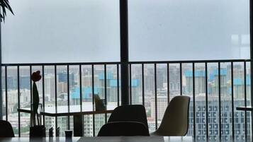 A room with a large window, a balcony with a railing, and a view of a cityscape.