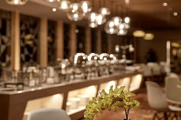 Un interior de restaurante con una larga mesa de comedor, sillas y luces colgantes.