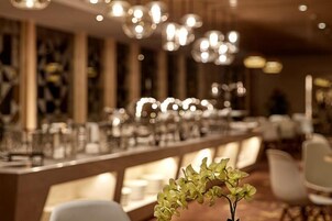 Un interior de restaurante con una larga mesa de comedor, sillas y luces colgantes.