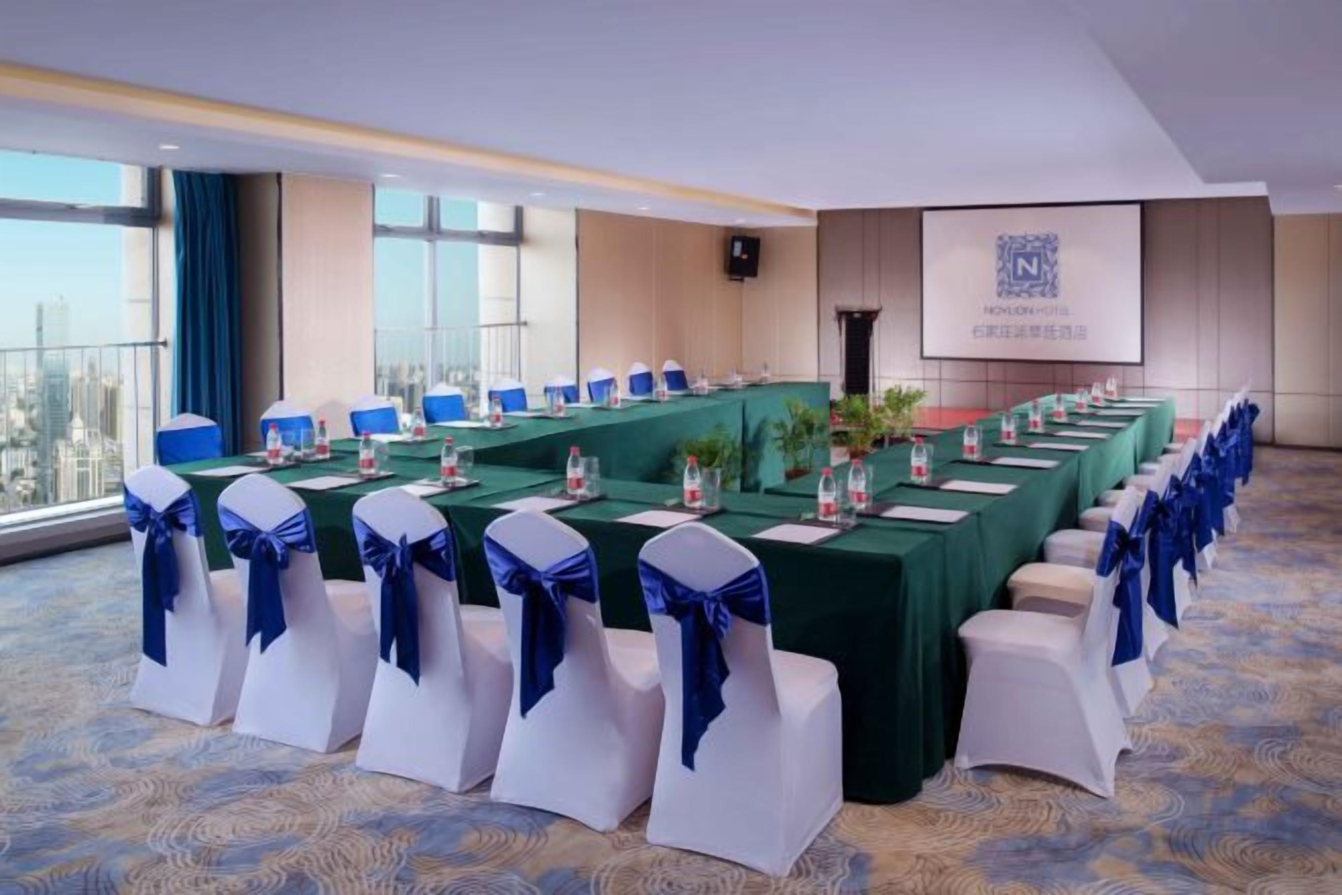 A conference room with a long table, chairs, and a screen displaying a logo.