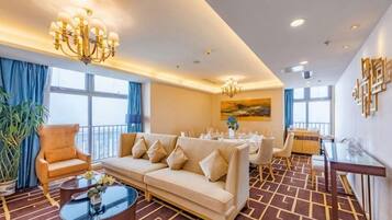 A hotel room with a sofa, a dining table, and a chandelier.