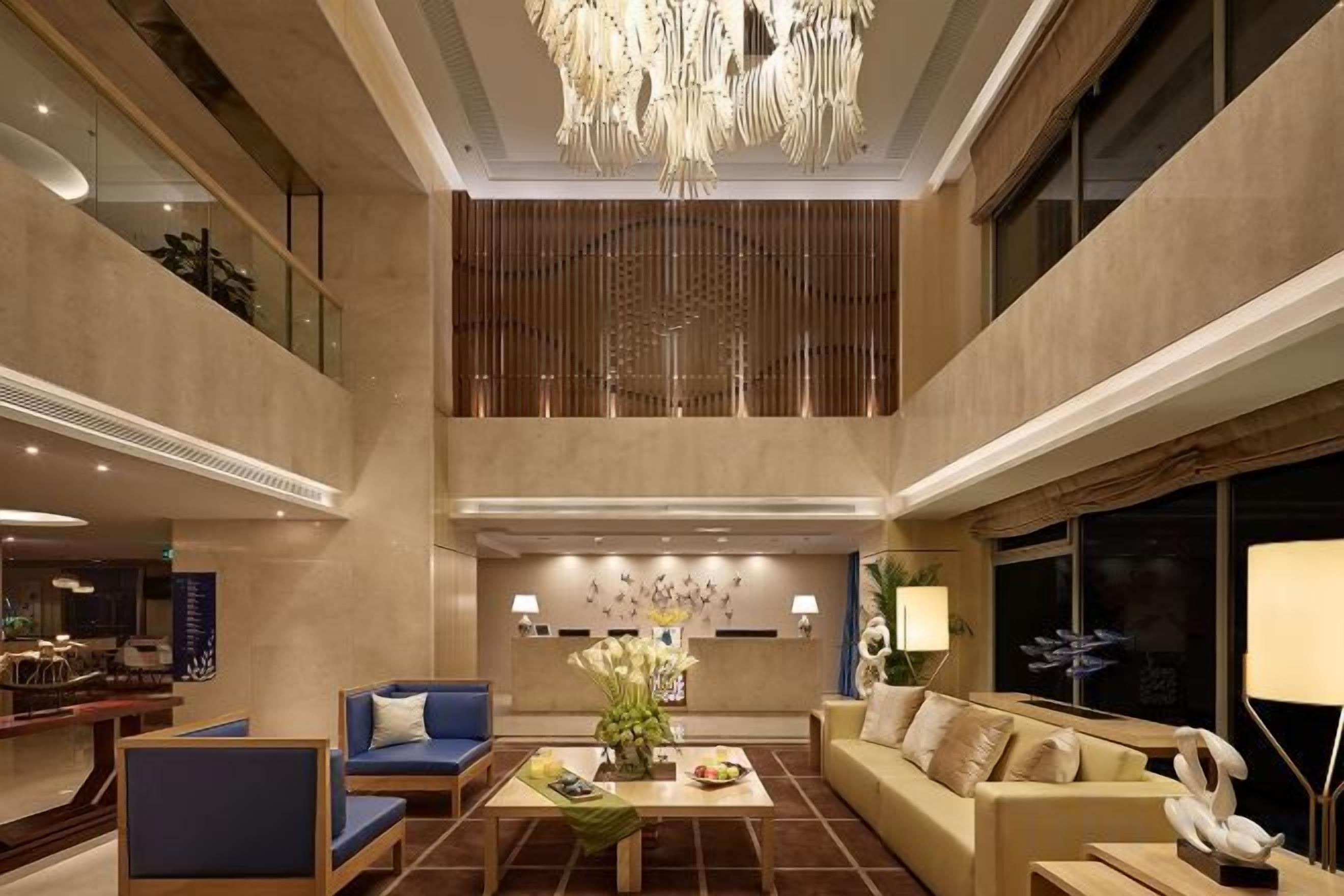 A spacious lobby with a high ceiling, a chandelier, seating areas, and a large window.