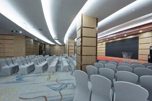 A conference room with rows of chairs, a stage with a screen, and a carpeted floor. - Wenshang Changjiang Hotel (Lanzhou)