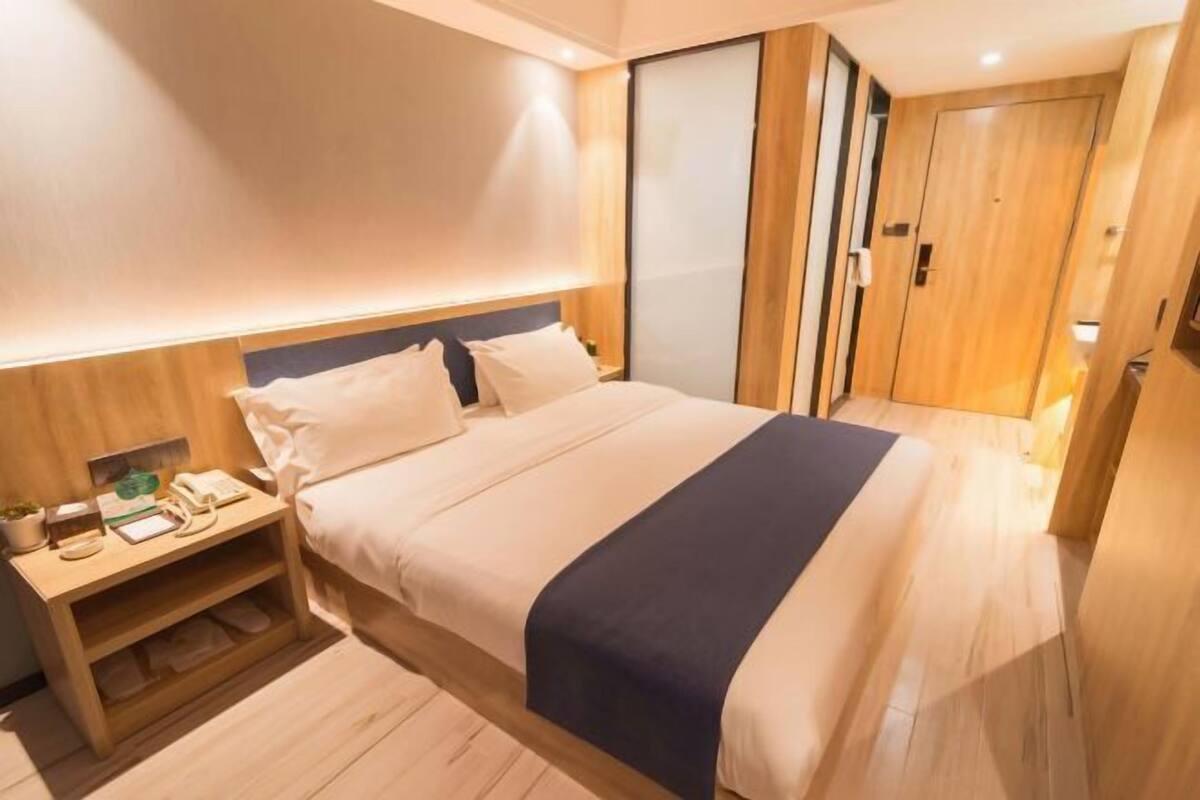 Una habitación de hotel moderna con una cama grande, una mesita de noche con lámpara y un armario con puerta corredera.