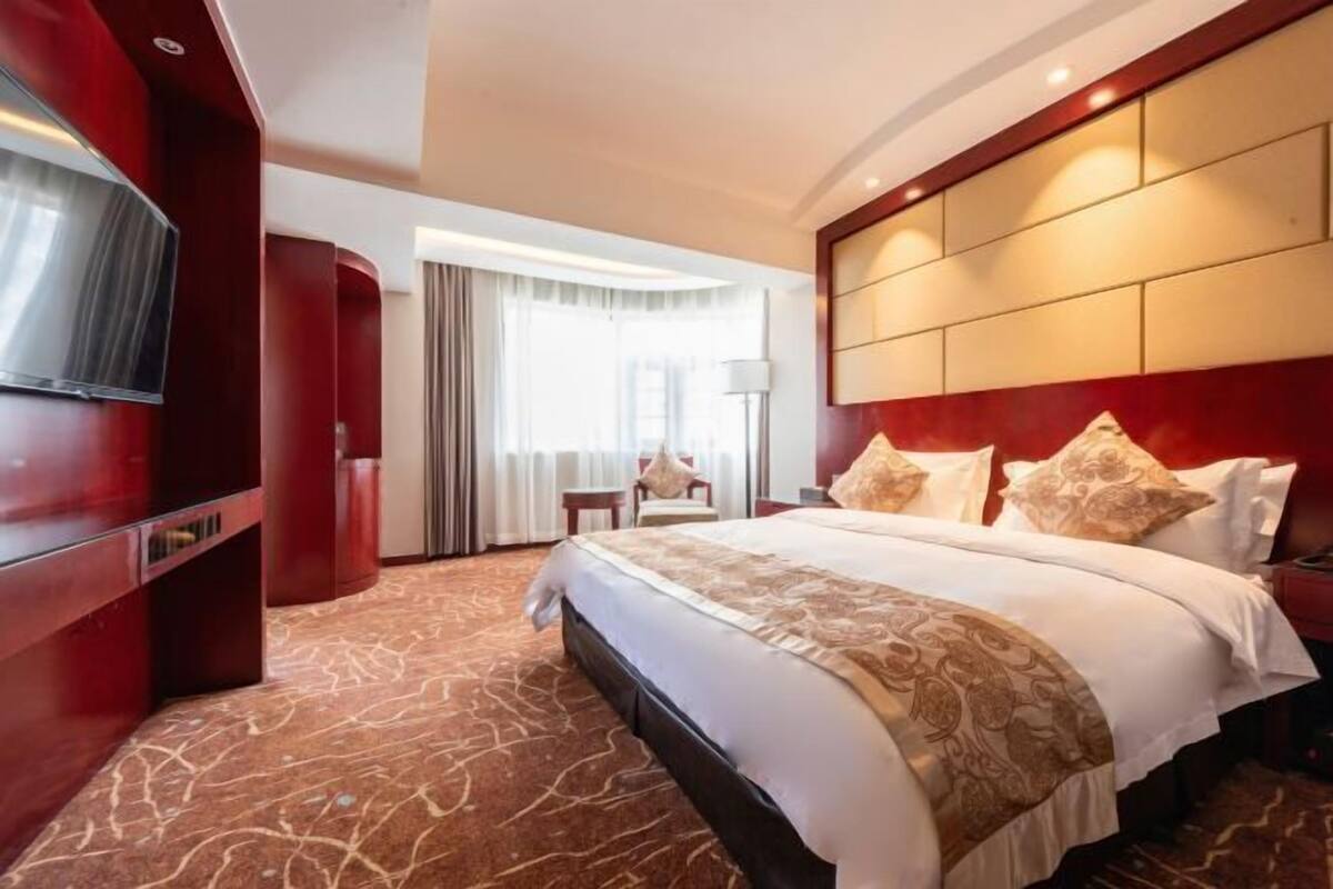 Una habitación de hotel con una cama grande, televisión, escritorio y silla.