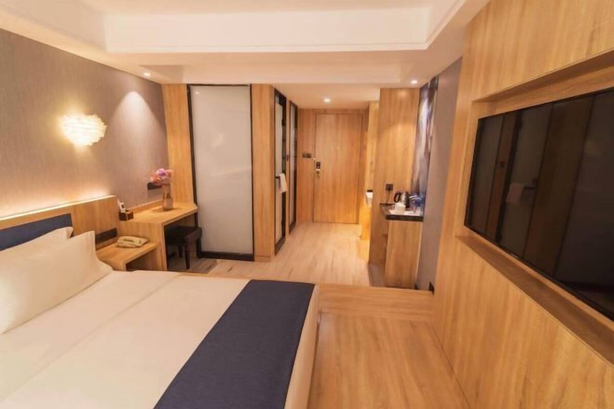 Una habitación de hotel con cama, escritorio, silla, televisión y baño.