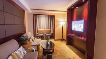Een hotelkamer met een bank, fauteuils, een kleine tafel, een televisie en een lamp.
