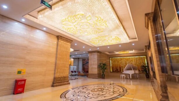 Un hall con techo estampado, diseño de piso circular y zona de recepción con un piano.