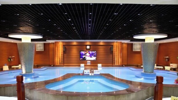 A large indoor swimming pool with a central viewing area, surrounded by wooden walls and seating. - Fangzhou Hotel (Kunming)