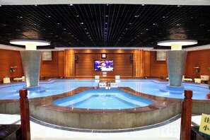 A large indoor swimming pool with a television screen in the background. - Fangzhou Hotel (Kunming)