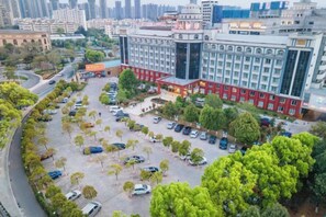 A multi-story building with a parking lot and trees. - Fangzhou Hotel (Kunming)