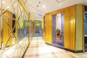 A hotel corridor with a check-in counter, a reception desk, and a decorative wall with a fountain. - Fangzhou Hotel (Kunming)