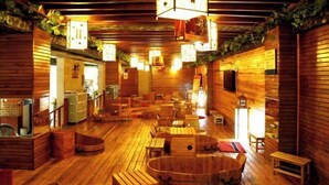 A wooden interior with a central hot tub, wooden benches, and tables. - Fangzhou Hotel (Kunming)