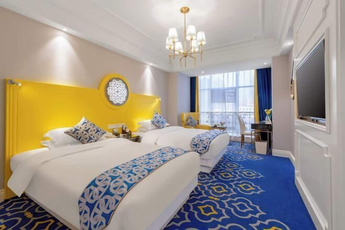 A hotel room with a large bed, a desk, and a view of the city.
