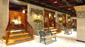 A hotel lobby with wooden staircases, benches, and decorative wall panels. - Fangzhou Hotel (Kunming)