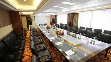 A conference room with a long table, chairs, and a projector screen.