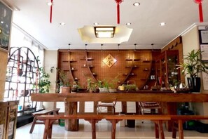 A restaurant with a wooden interior, a central table, and shelves with plants. - Fangzhou Hotel (Kunming)