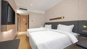 A hotel room with two beds, a TV mounted on the wall, a bedside table, and a modern design. - Jinjiang Inn (Beijing)