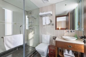 A modern bathroom with a glass shower enclosure, a white toilet, a vanity with a sink, and a mirror.