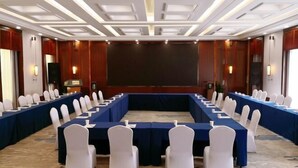 A conference room with a long table, white chairs, and a large screen. - Piaget Hotel (Anqing)