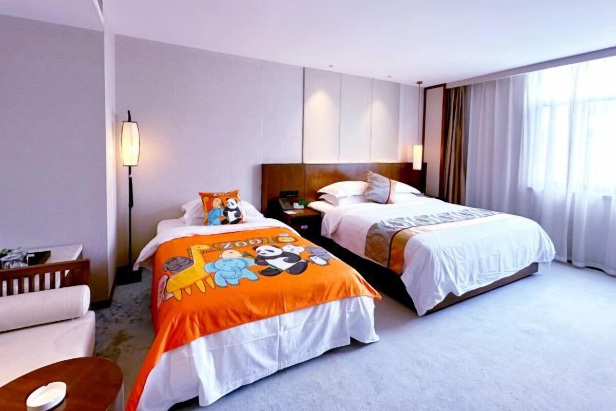 A hotel room with two beds, a desk, and a chair.