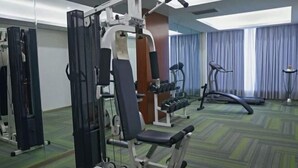 A gym with exercise equipment, a treadmill, and a mirrored wall. - Piaget Hotel (Anqing)