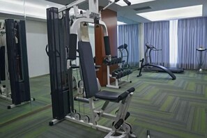 A gym with exercise equipment, a treadmill, and a mirrored wall.