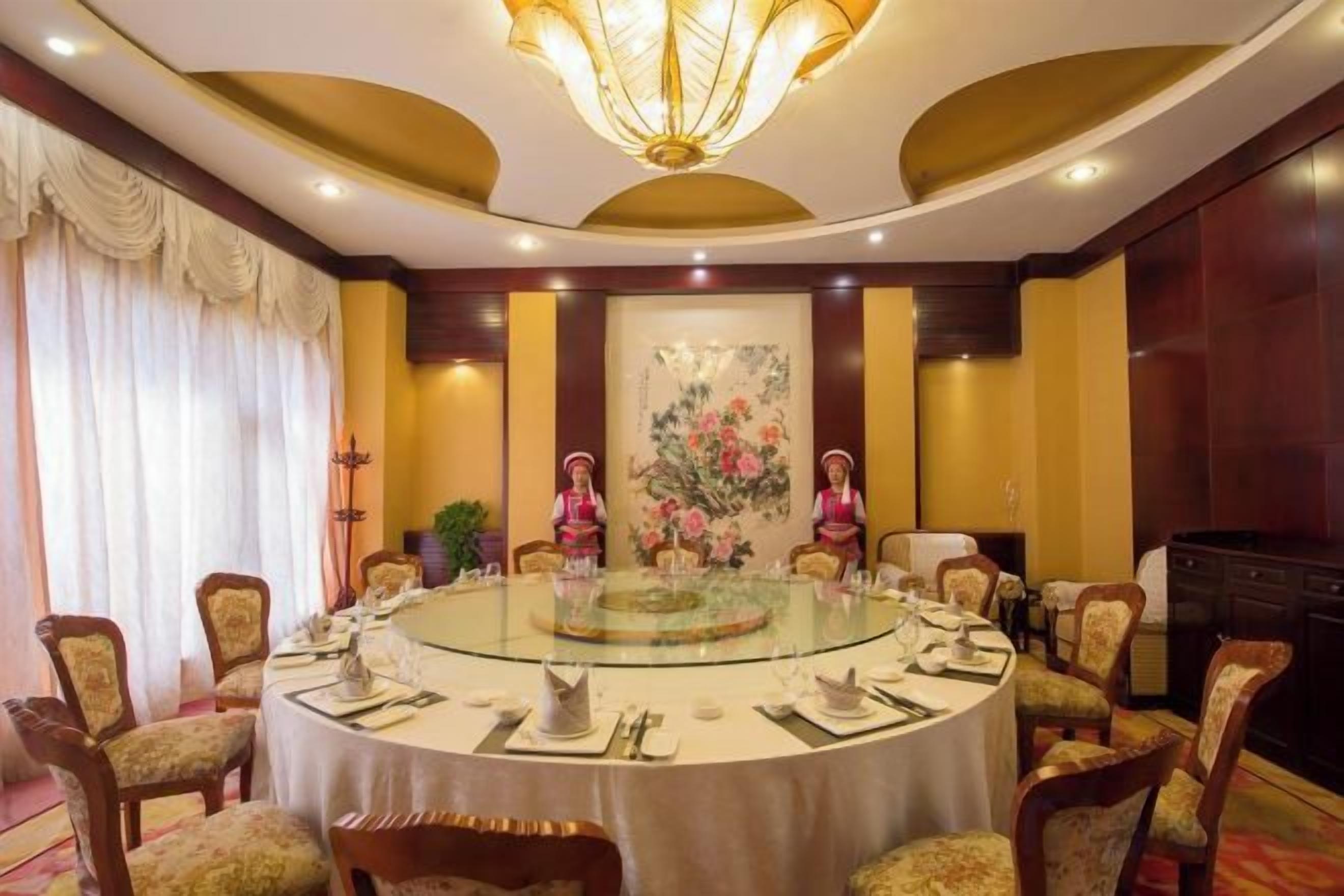Un salón de conferencias con una mesa redonda, sillas y una araña.