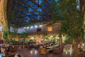 A spacious indoor area with a high ceiling and a glass structure, furnished with sofas and tables, and surrounded by plants. - Cangshan Hotel (DALI)