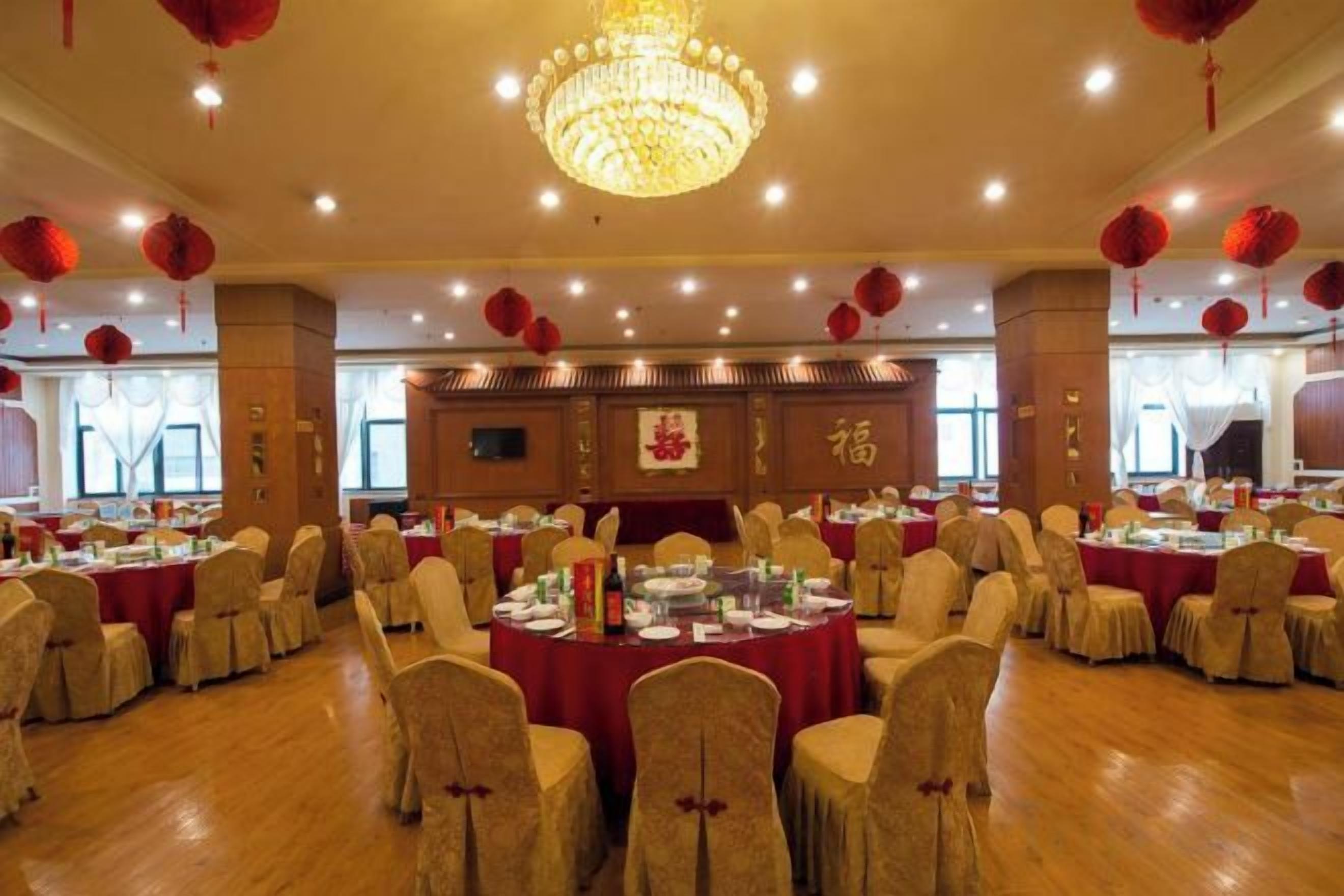 Un salón de banquetes con mesas redondas, sillas y una araña.