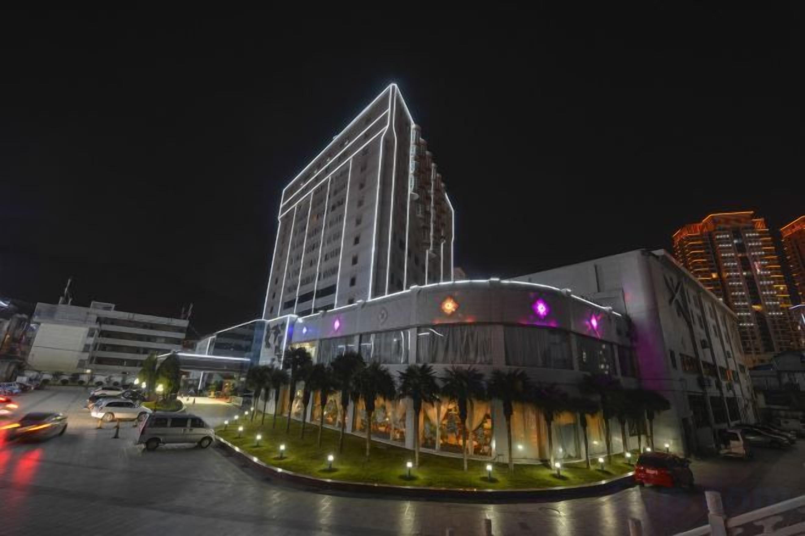 Un hotel con diseño moderno, que destaca por un edificio en esquina y una zona de estacionamiento.
