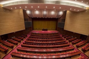 A large auditorium with tiered seating, a stage, and a curved ceiling. - Cangshan Hotel (DALI)