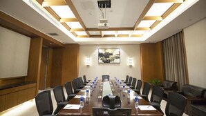 A conference room with a long table, chairs, a projector, and a large painting on the wall. - Mingfa International Hotel (Hefei)