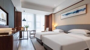 A hotel room with two beds, a desk, and a TV. - Mingfa International Hotel (Hefei)