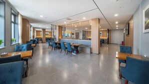 A modern hotel lobby with a central bar area, seating arrangements, and large windows. - Ruiyang Crown Hotel (Yining City)