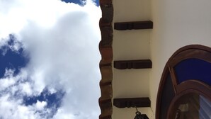 A building with a white facade, a red brick wall, and a window with a blue frame. - Villa Pepita Real (Villa de Leyva)