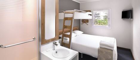 Une chambre d’hôtel moderne équipée d’un lit superposé, d’un téléviseur près du lit, d’un grand miroir et d’une fenêtre donnant sur la forêt.