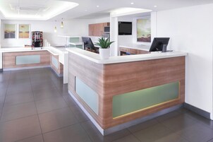 Una zona de recepción moderna con un mostrador de madera, una máquina de café y un televisor de pantalla plana.